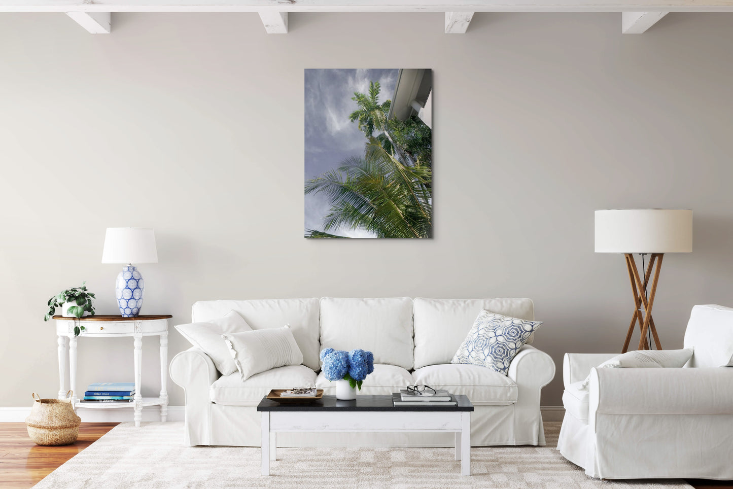 Palm Tree Dreaming Canvas Wall Art in lounge room with white walls, white lounge and chair, white pillows, wooden coffee table, rug, wooden side table, blue lamp, white floor lamp and wooden floorboards