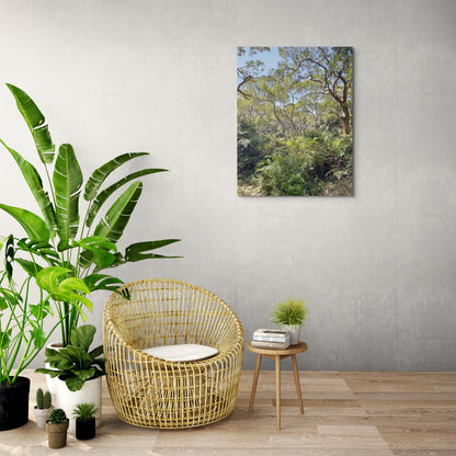 Rainforest Canvas Wall Art in lounge room with grey wall, wicker chair, wooden side table, several pot plants and wooden floorboards